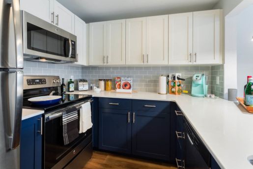 kitchen with stainless steel oven and fridge, gray brick tile,white and blue color scheme
